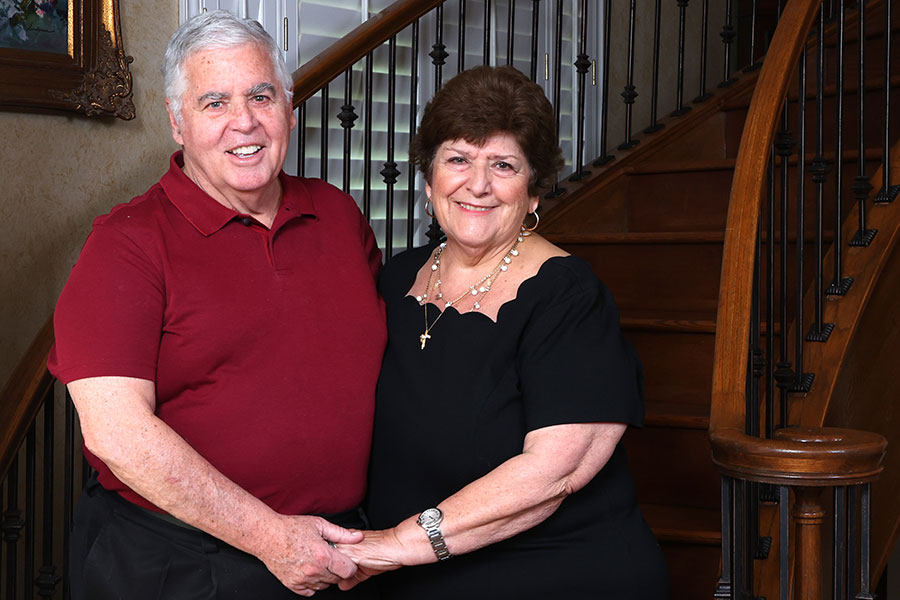 The Quinn couple stand before a winding staircase in their home
